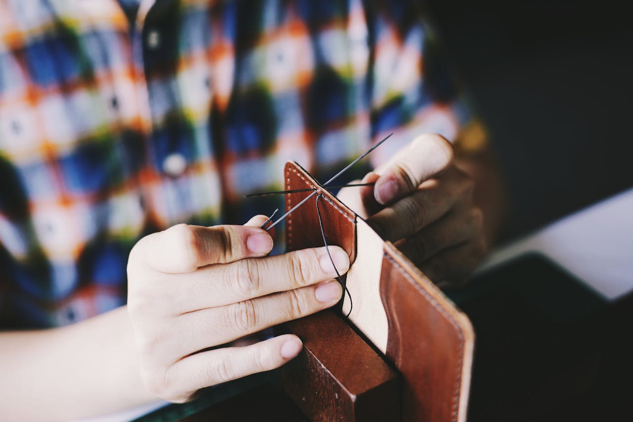 story-02 Close-up of a person hand-stitching leather, showcasing detailed craftsmanship and DIY skills.