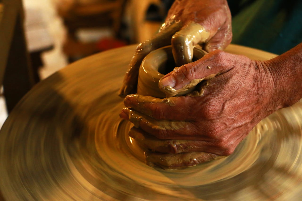 services-03 Close-up of hands shaping clay on a pottery wheel, highlighting the art of ceramics.